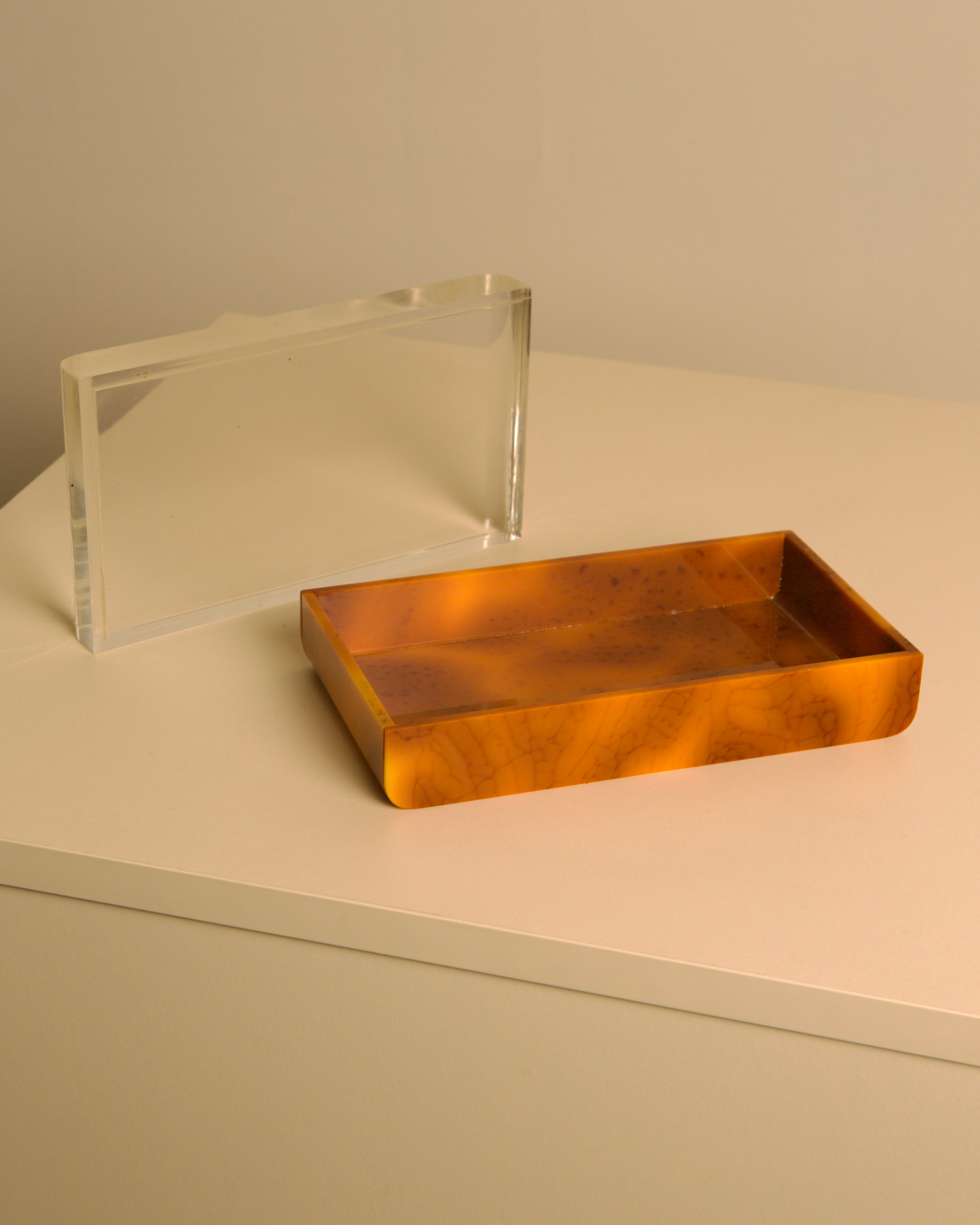 Italian 70s trinket tray and box in brown bakelite — side angle on neutral surface