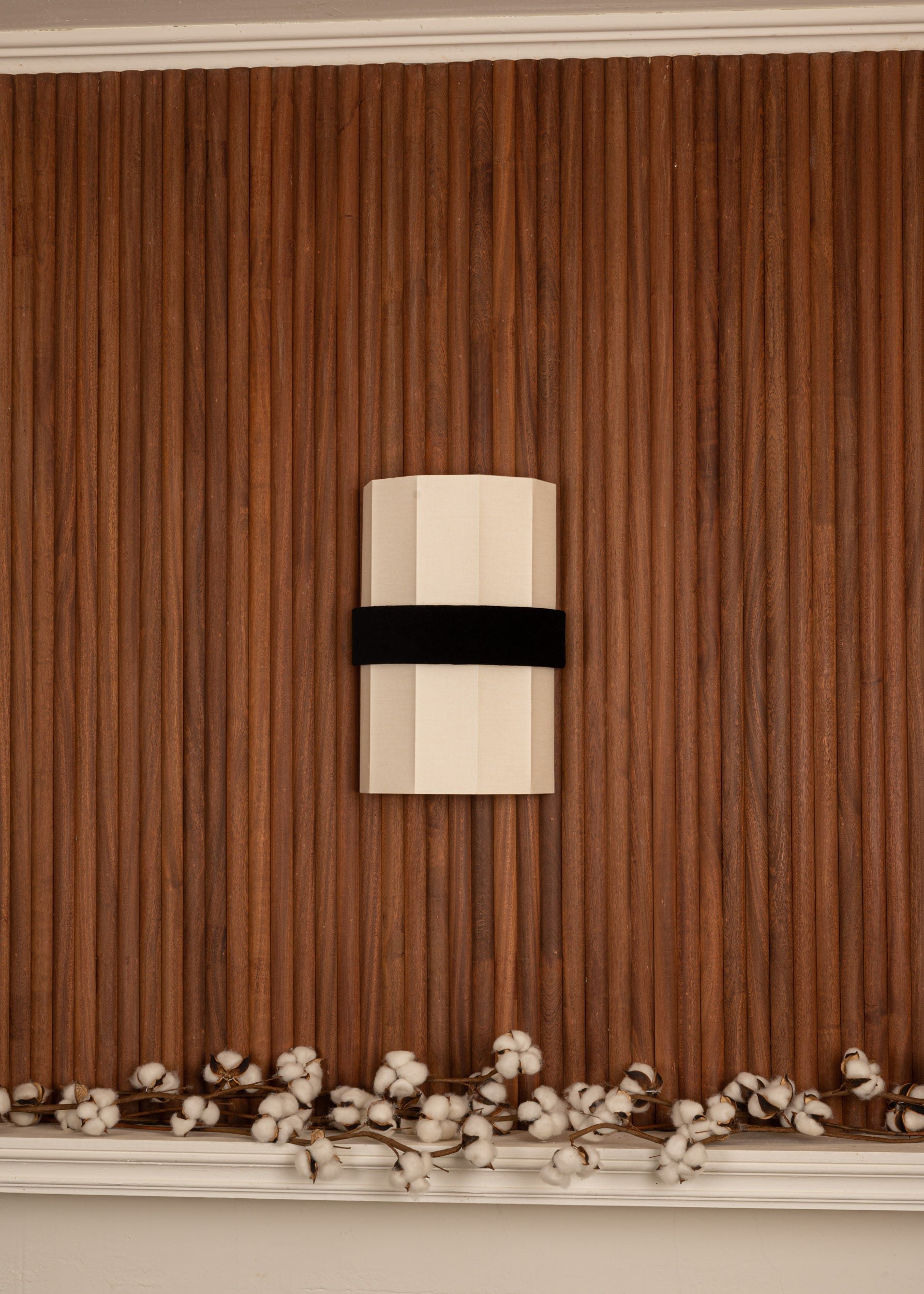 Okla black velvet wall light mounted on vertical wood paneling