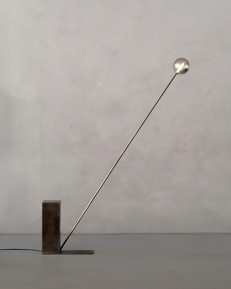 Oblique Glow floor lamp with angled brass arm and sphere bulb