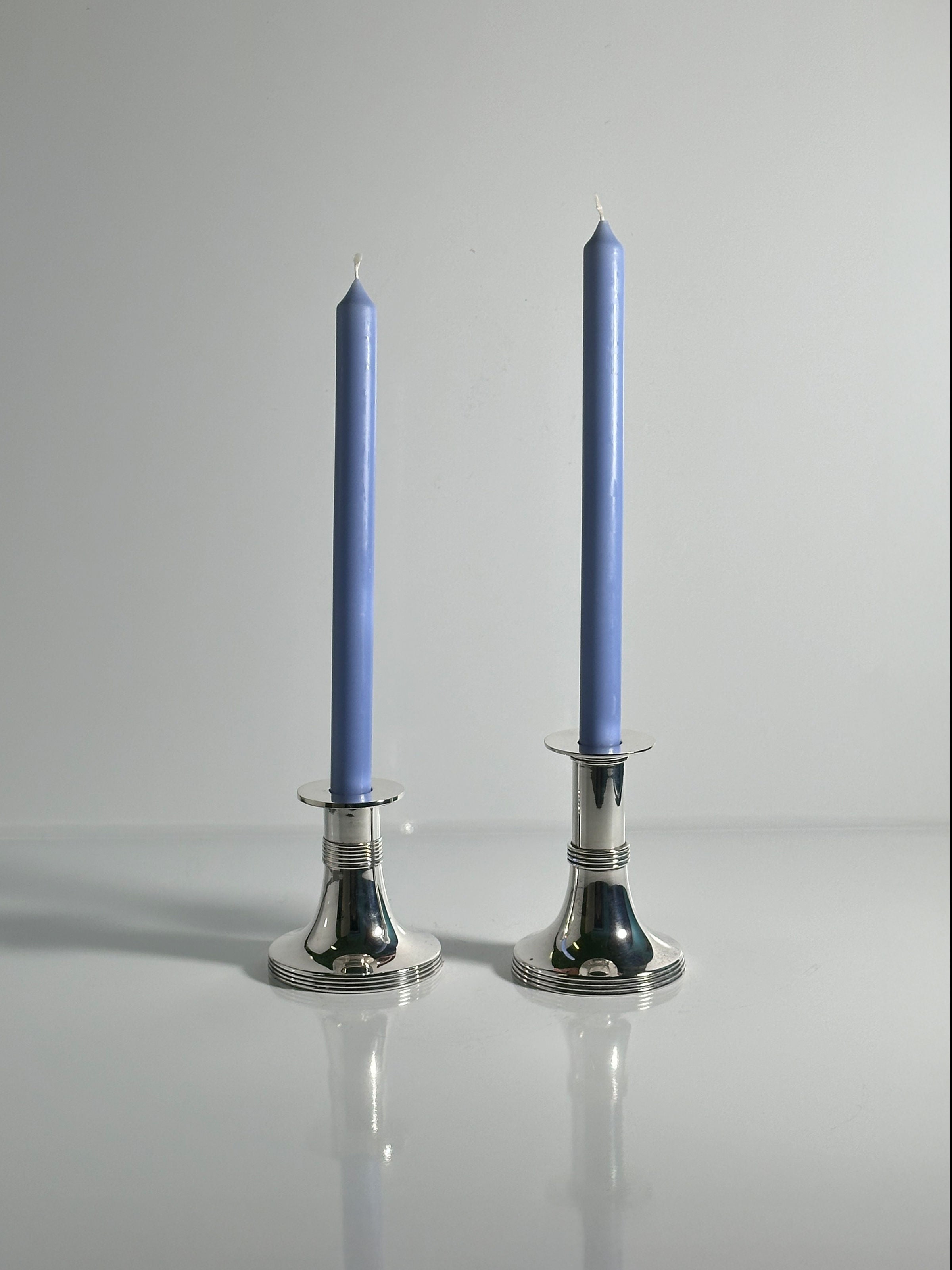 Pair of Silver Plated Candleholders by Gunther Lambert — close-up of polished silver surface with blue candles