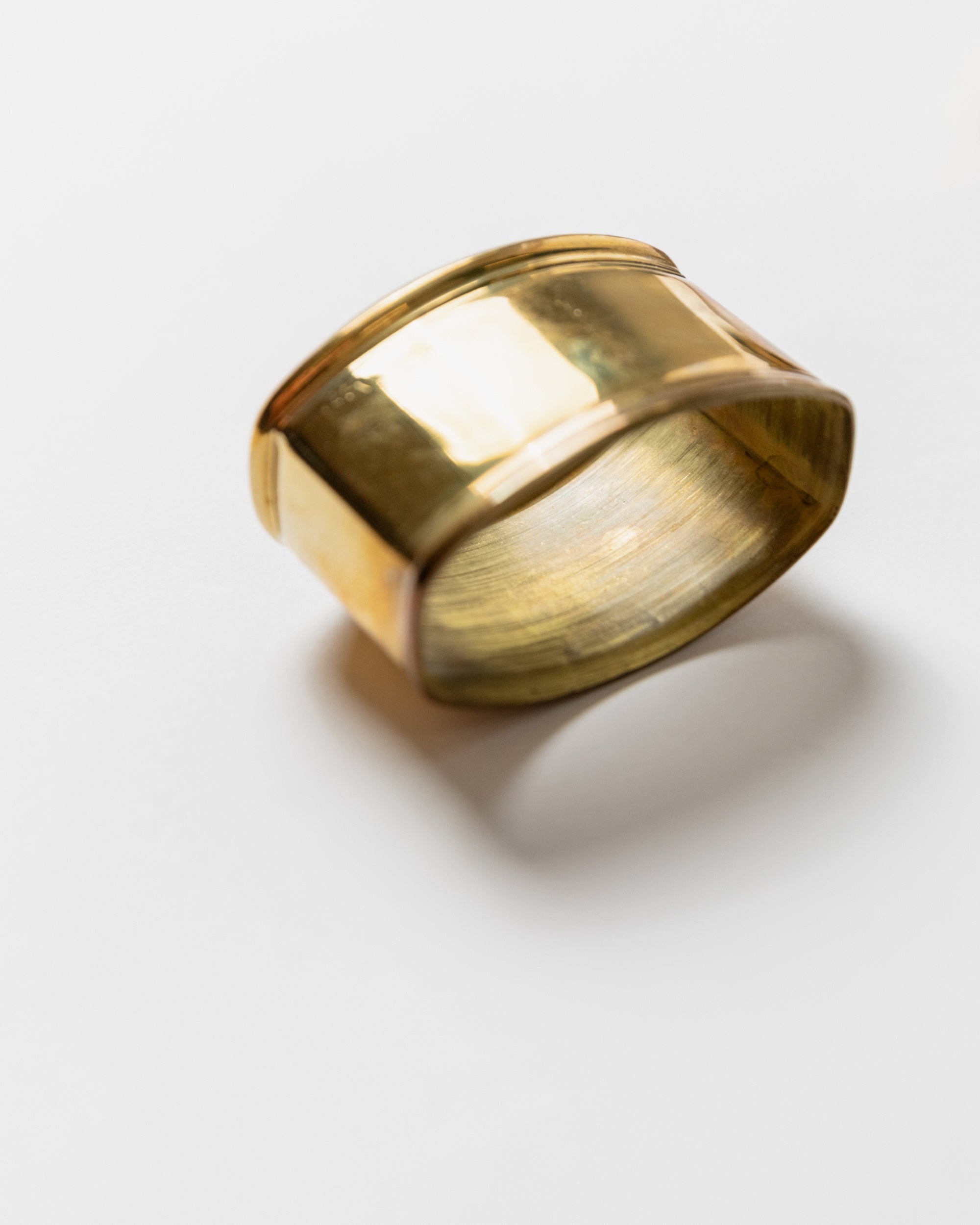 Close-up detail of polished brass napkin ring showing curved form