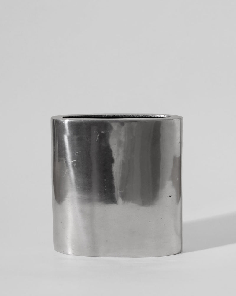 The Vintage Stories Polished Aluminum Square Flat Vase stands upright against a plain light gray background, its shiny, smooth surface evoking the elegance of classic 1960s decor.