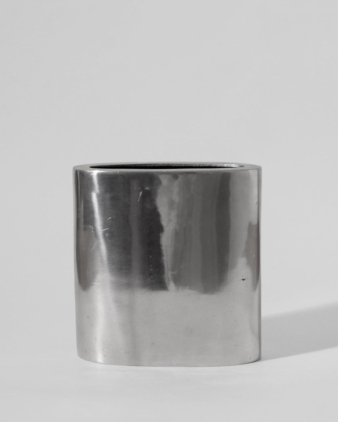 The Vintage Stories Polished Aluminum Square Flat Vase stands upright against a plain light gray background, its shiny, smooth surface evoking the elegance of classic 1960s decor.