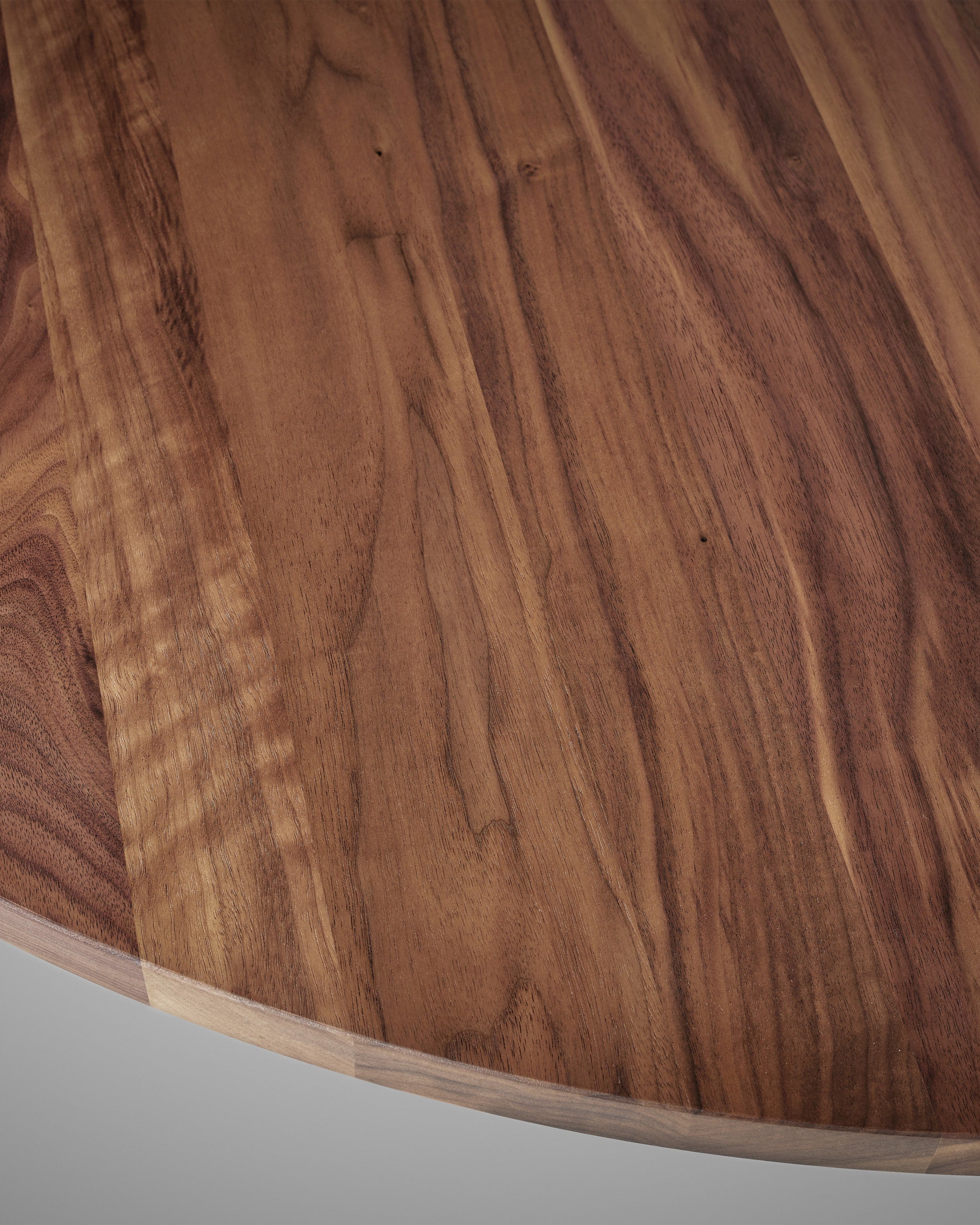 Close-up walnut wood grain detail of Aperta round table surface