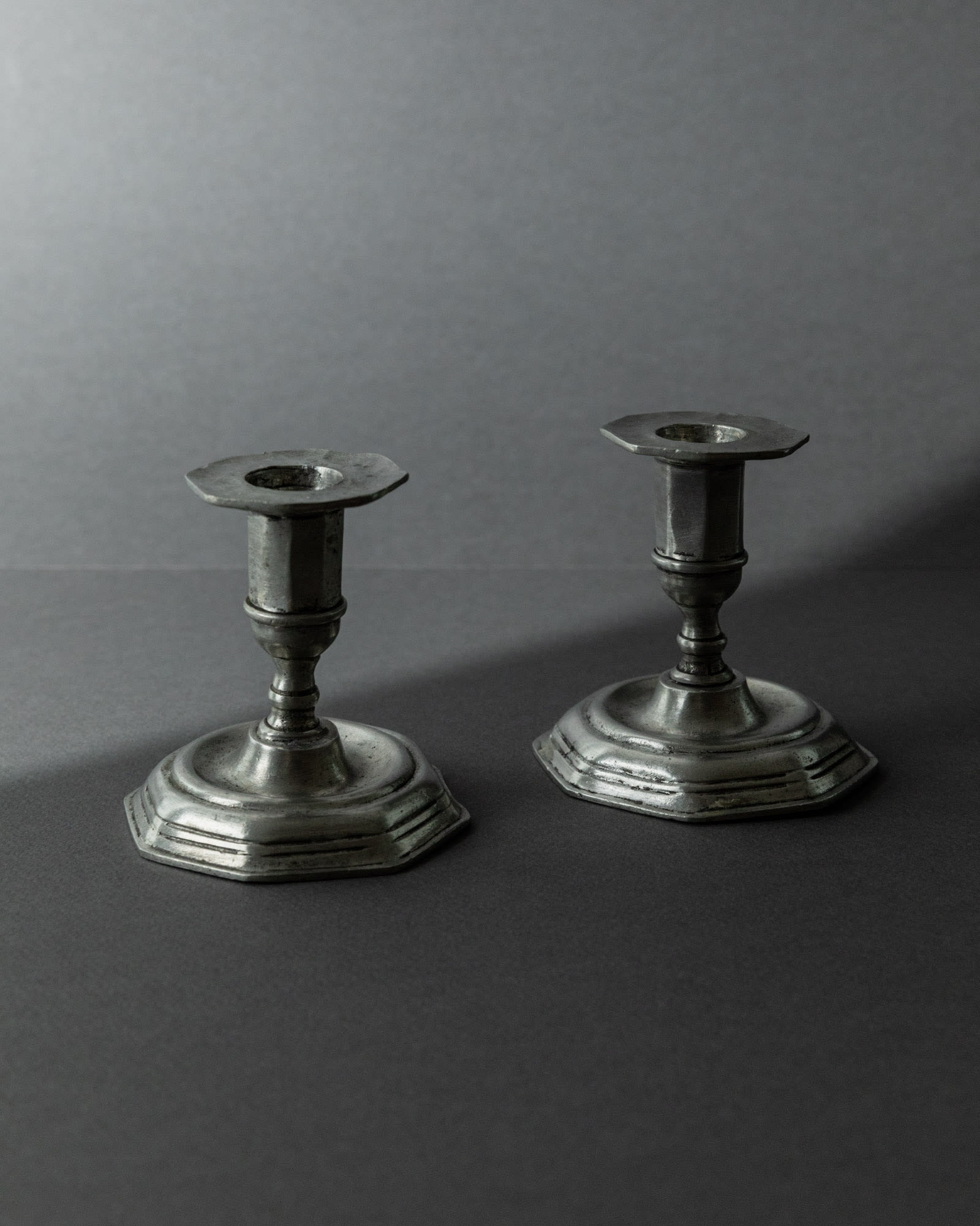 1900s Pewter Candleholders Set of 2 — angled view on gray background