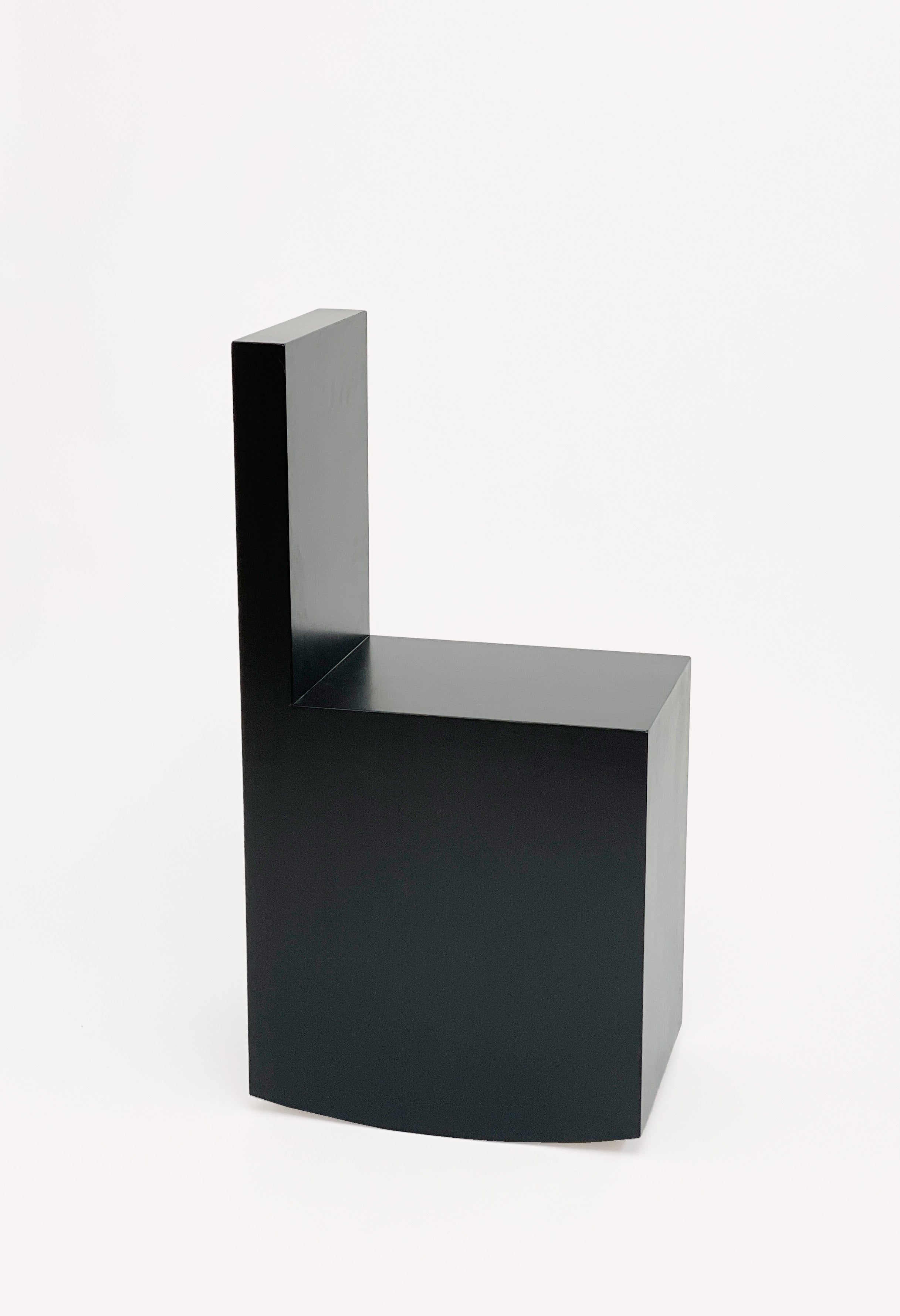 The Art Rocker Chair by GOONS is a minimalist black chair with a geometric, block-like design and right angles, crafted by the Paris-based studio GOONS, shown against a plain white background.