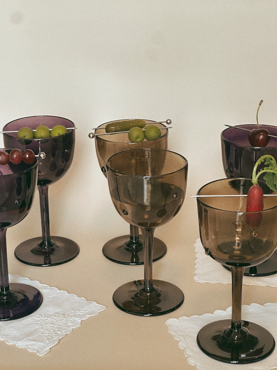 NOA GOBLET cocktail Glass — side angle with assorted garnished drinks