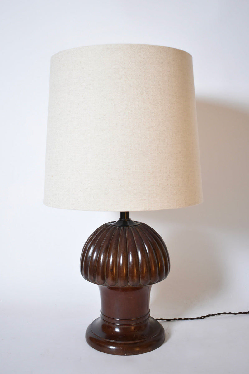 The Barracuda Interiors Pine Shape Wooden Lamp, 1930s, features a ribbed dark wood base and a large off-white cylindrical shade. It sits on a white surface with its black power cord visible.