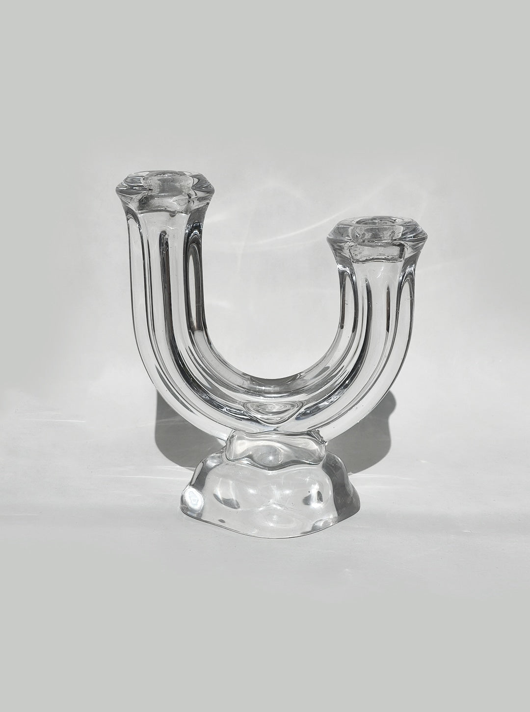 Clear glass arch-shaped candle holder with twin holders on base