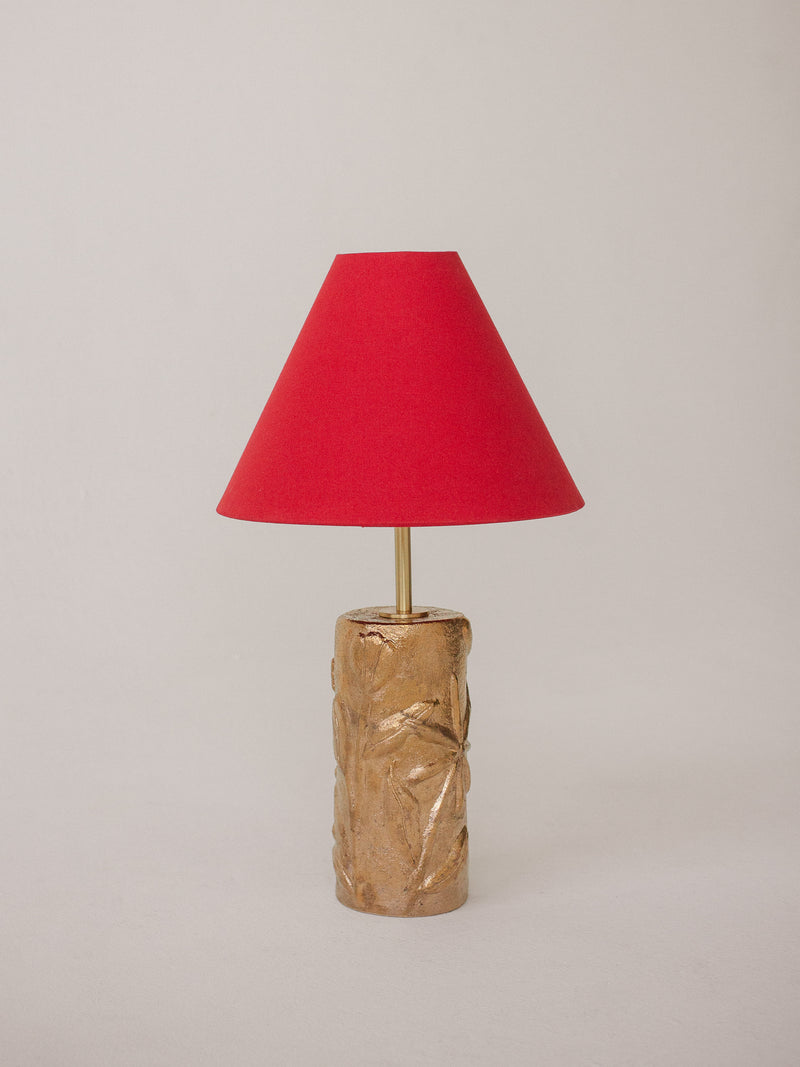 Gold ceramic table lamp with textured leaf design and red fabric shade