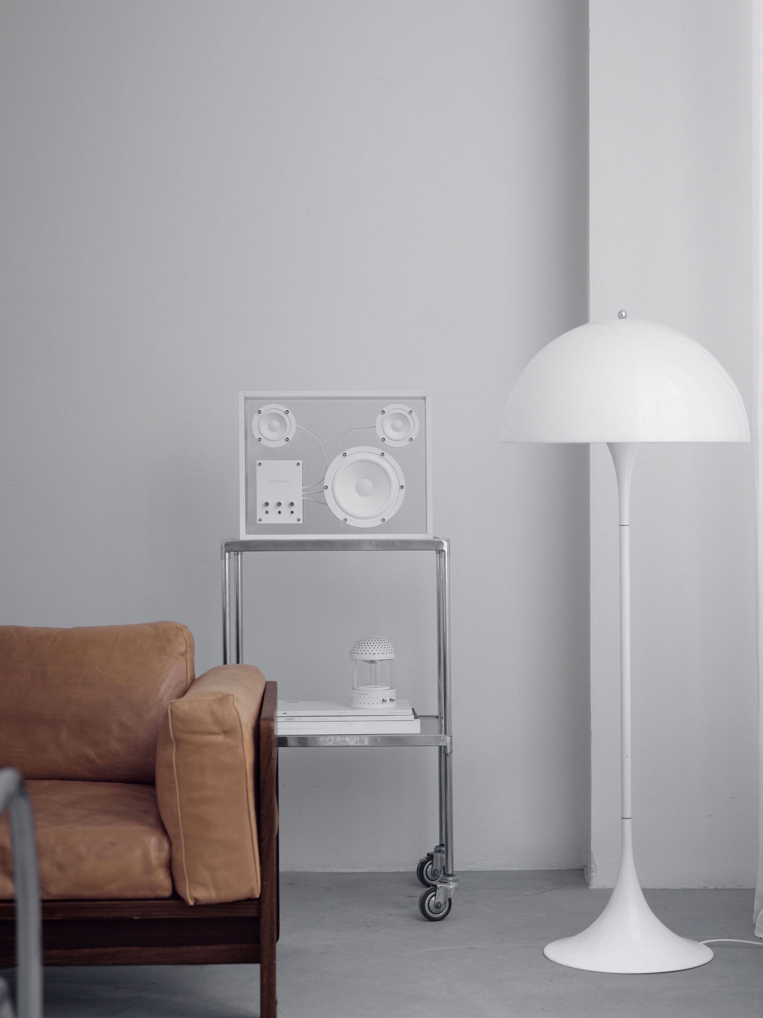 Transparent Speaker White - Bluetooth — side view on metal stand in minimalist room