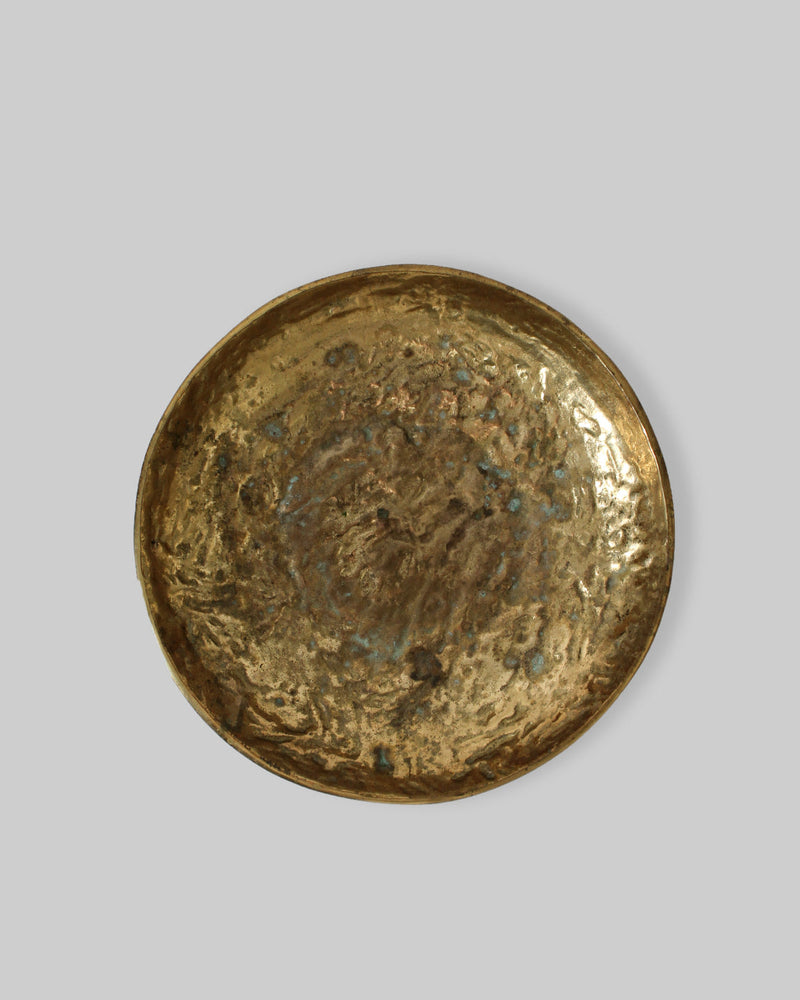The Massive Organic Textured Brass Bowl by Vintage Stories features a round, hammered surface with uneven edges and natural patina, evoking the character of a vintage 1950s Swedish bronze bowl against a plain gray background.