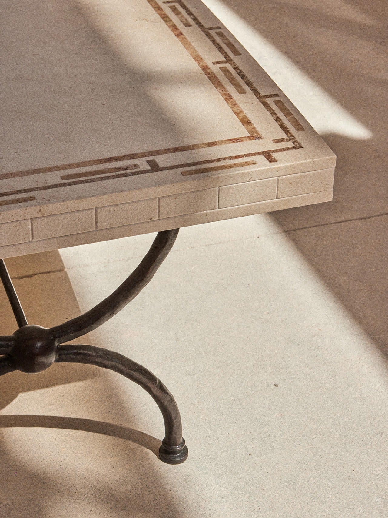 Greek Symposia Dining Table — side angle showing stone top and metal legs