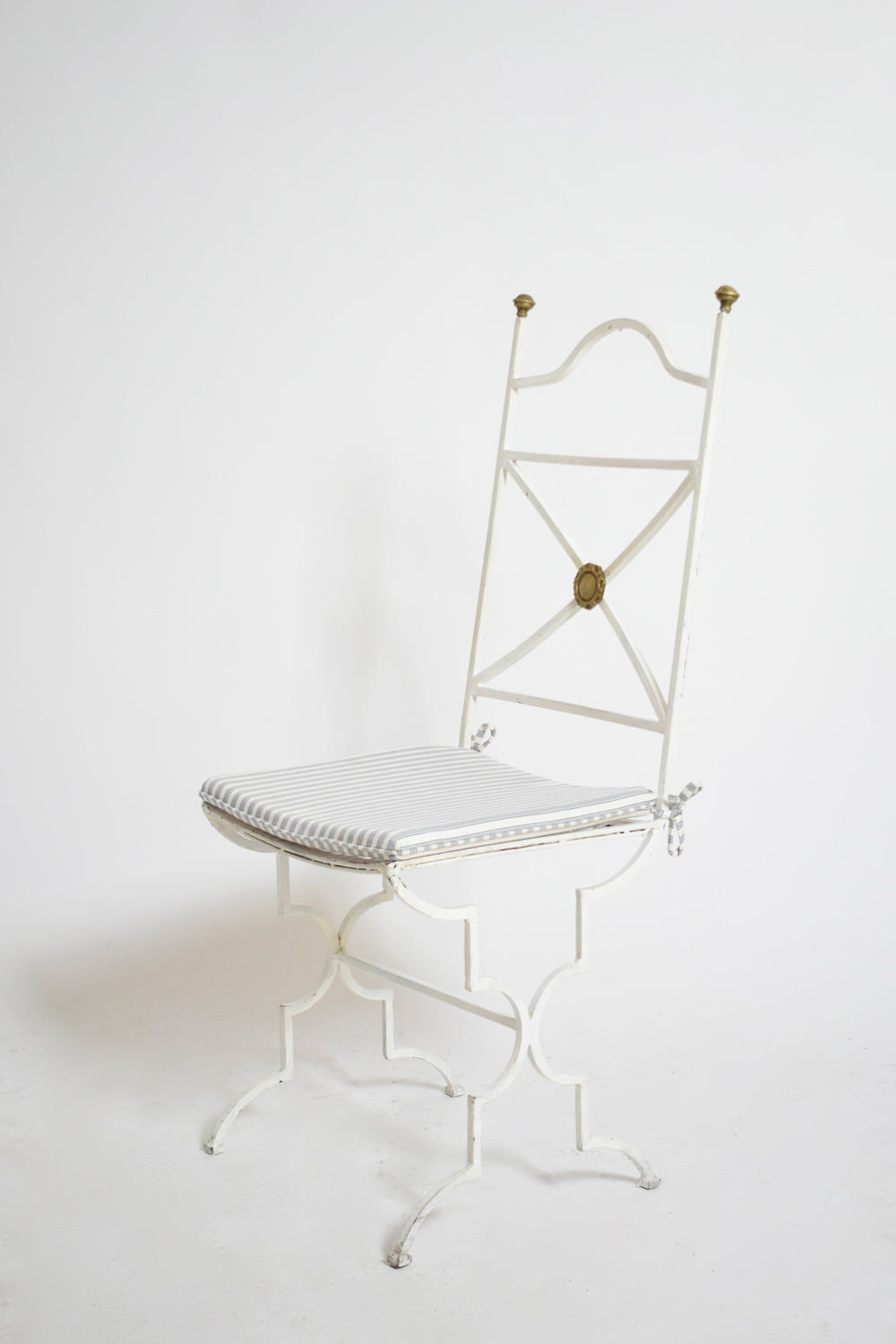 A Set of Four White Wrought Iron Chairs by Barracuda Interiors, 1940s, with decorative gold accents and striped seat cushions, is shown against a plain white background.
