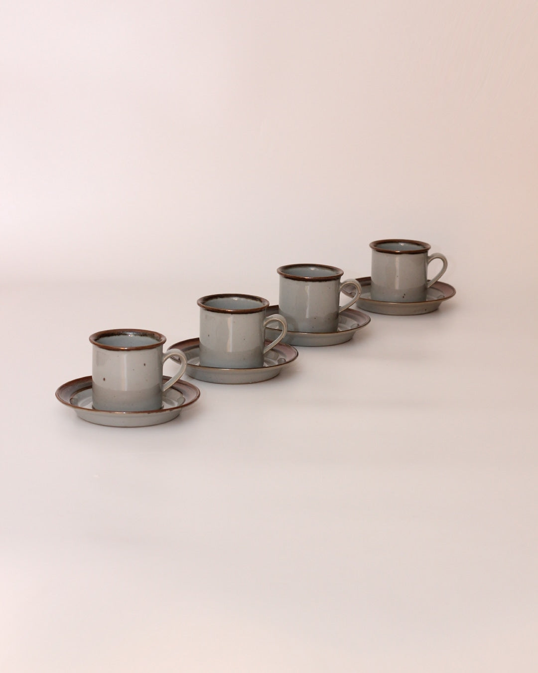 Set of Four Ceramic Cups with Saucers — side angle on neutral background