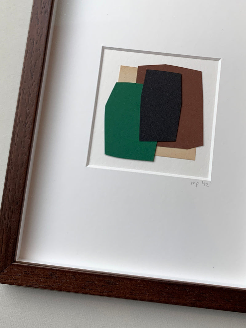 Green Composition - Paper Collage by Marie Pomme Adriaansen features overlapping green, black, brown, and tan geometric shapes on white paper in a simple wooden frame. The piece is signed "mp '22" in the bottom right corner.