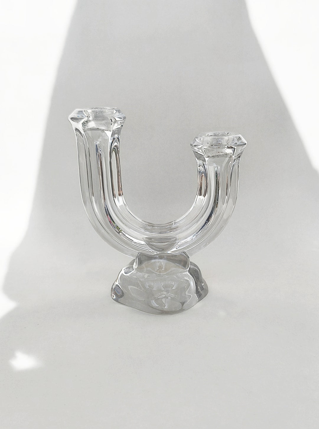 Clear glass arch-shaped candle holder with dual arms on base