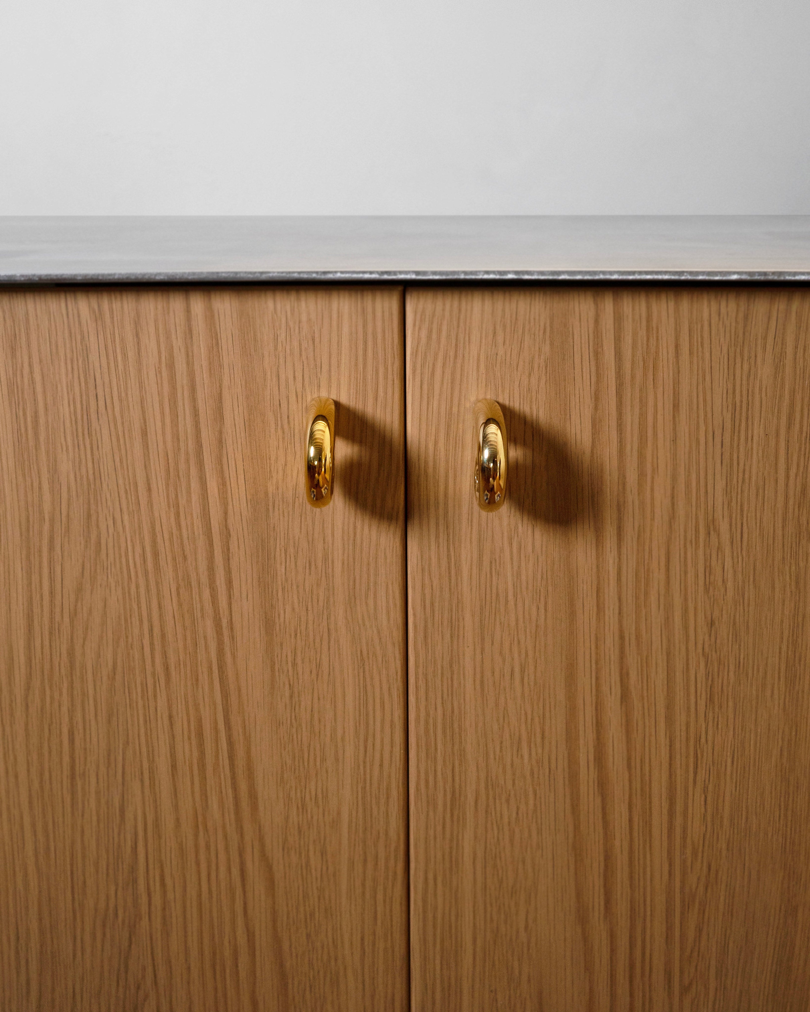Noelle Knob - Brass — back view on wooden cabinet doors