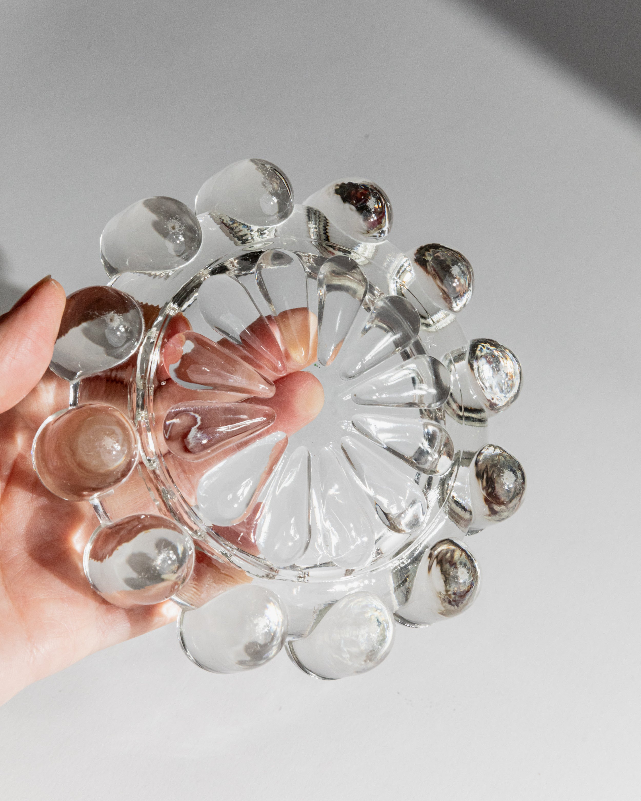 Hand holding vintage Italian glass ashtray showing circular design
