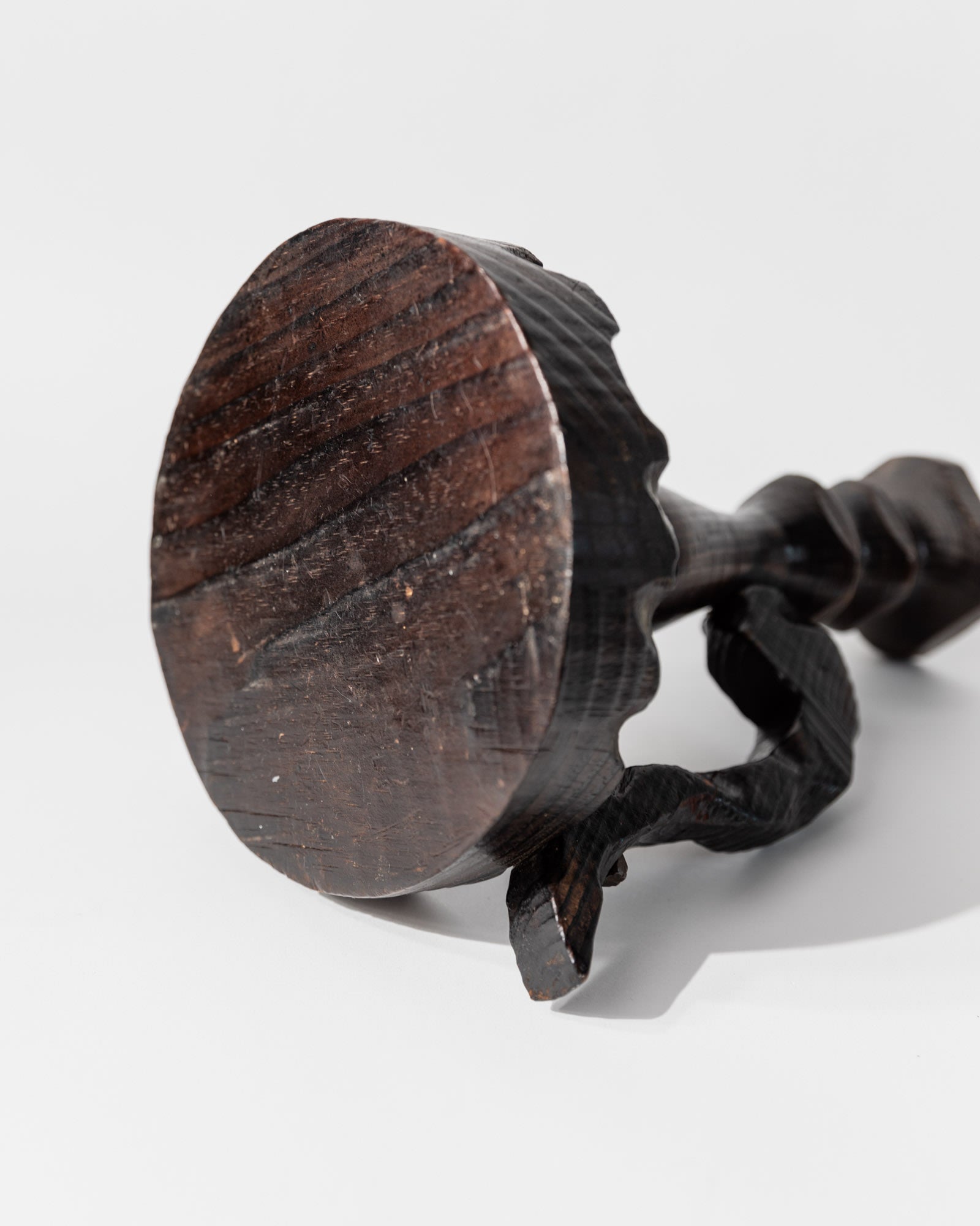 A close-up of the 1960s Wooden Candleholder in Handcarved Dark Wood by Bottega Jacobs, featuring a round, flat base and twisted handle with Brutalist design, set against a plain white background.
