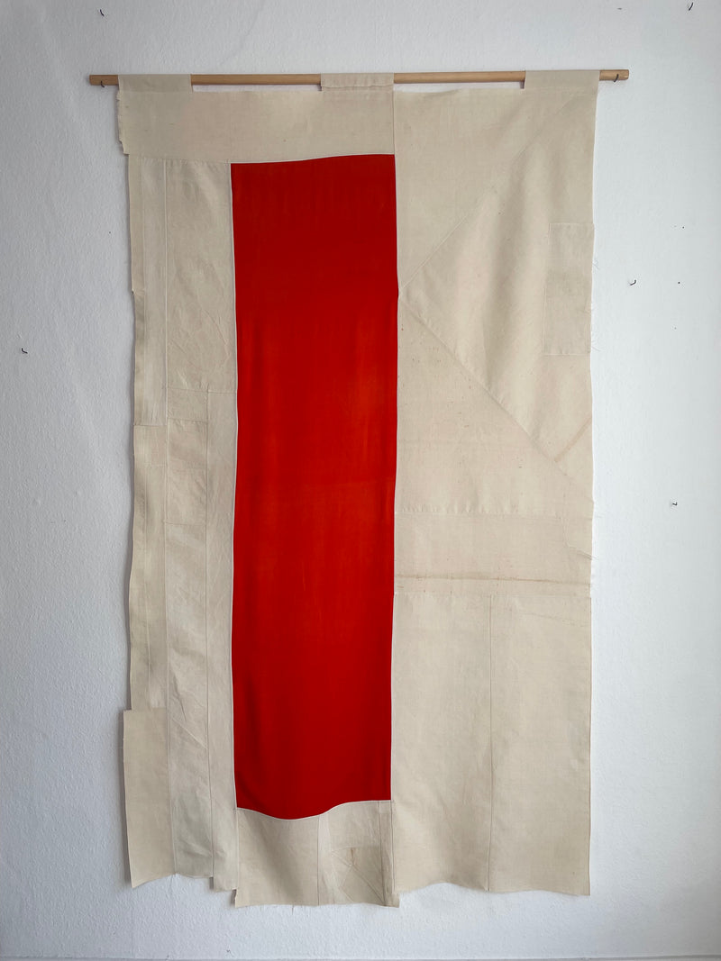 Contemporary textile art with vertical red stripe on cream fabric