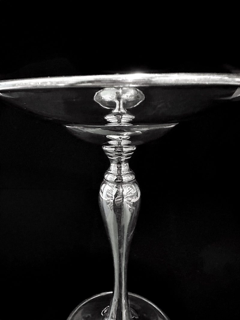 A close-up of the Dodo Vintage Heavy Silver-Plated Foot Bowl showcases its shiny stem and bowl with bright reflections, set against a black background.