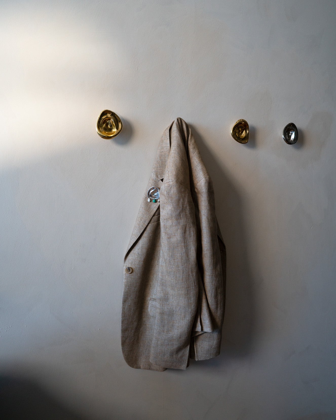 Ripple Hook - Small - Brass — top view with linen jacket hanging on wall