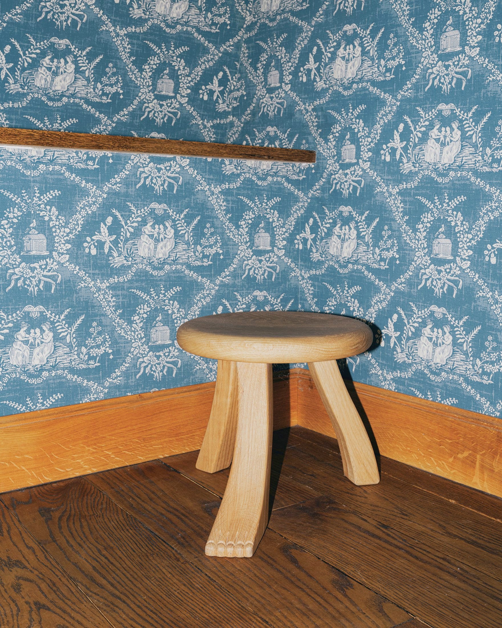 Foot Stool in Black Chestnut — angled view against patterned wallpaper