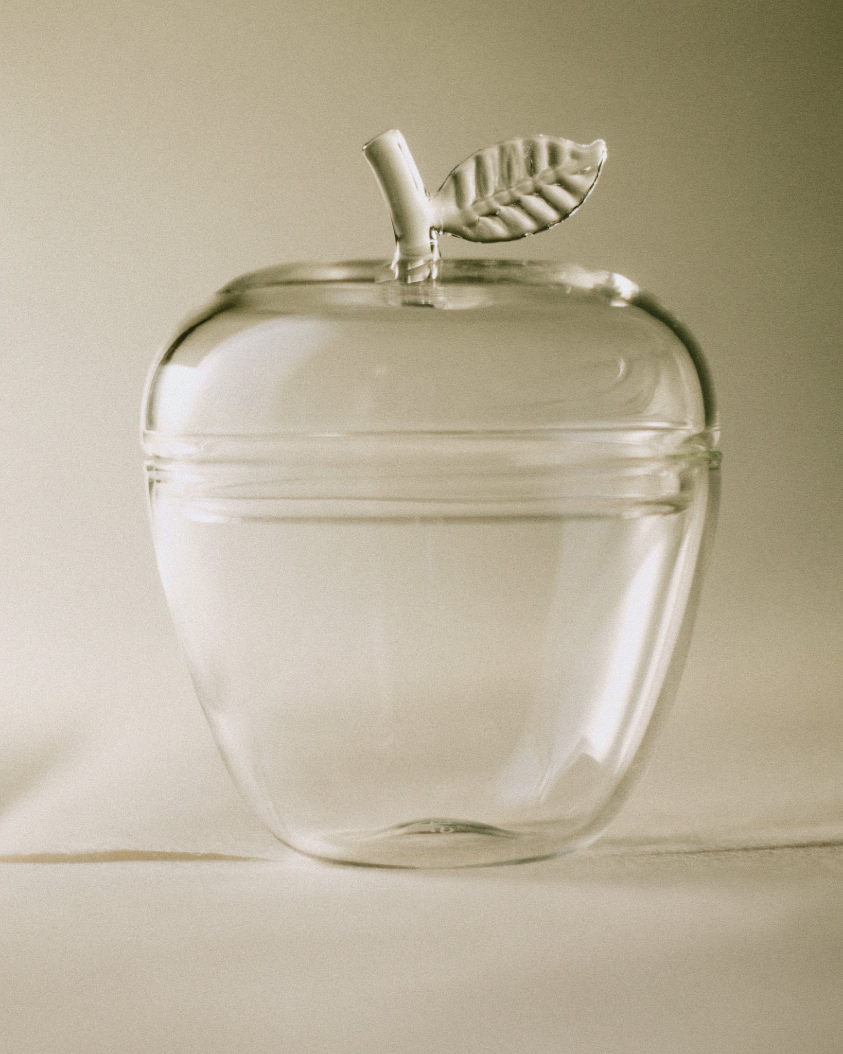 La Pomme — clear glass apple-shaped container on neutral background