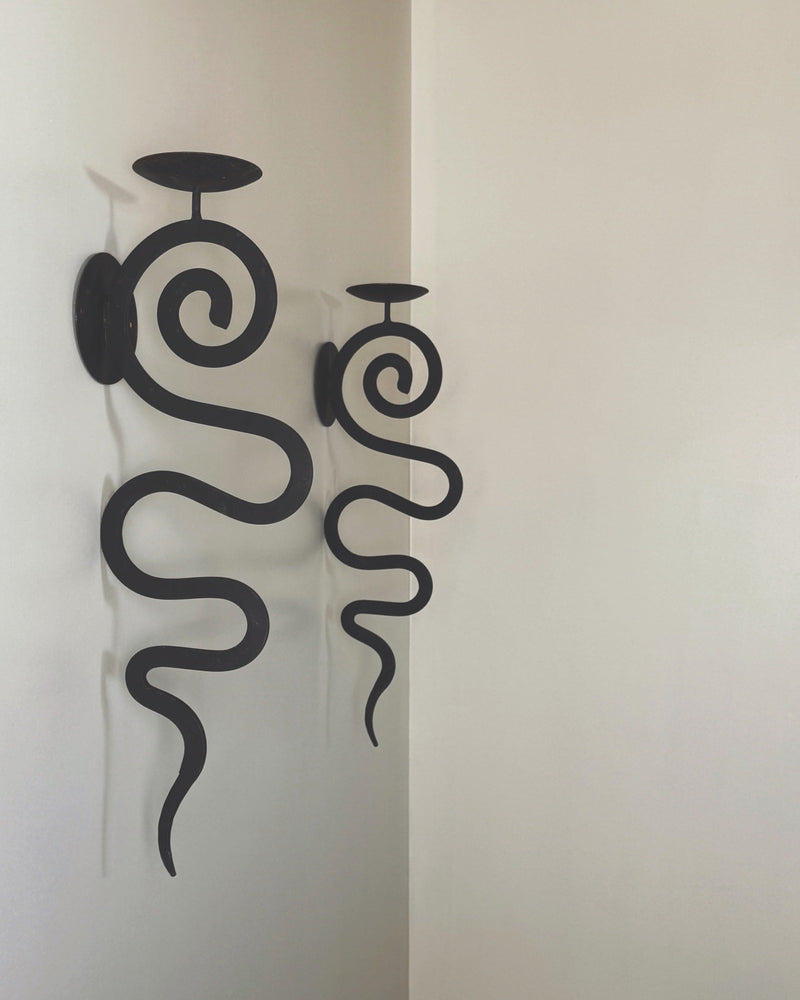 Black wrought iron wall sconces with spiral design and candle holders
