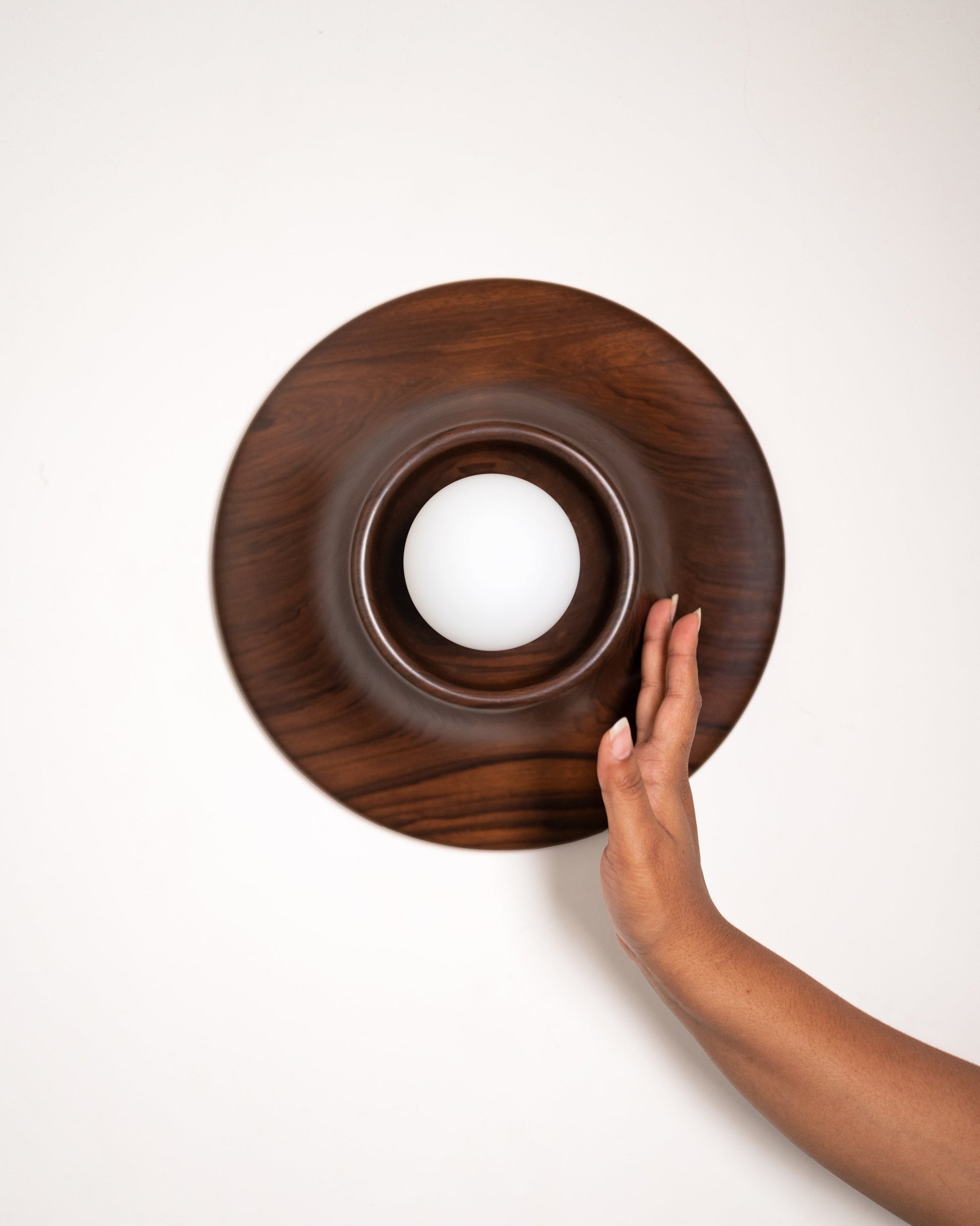 Paten Wall Light — hand touching walnut wood surface