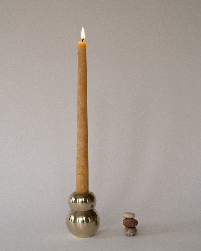 ANJOU Candleholder — brass holder with lit candle and stacked stones