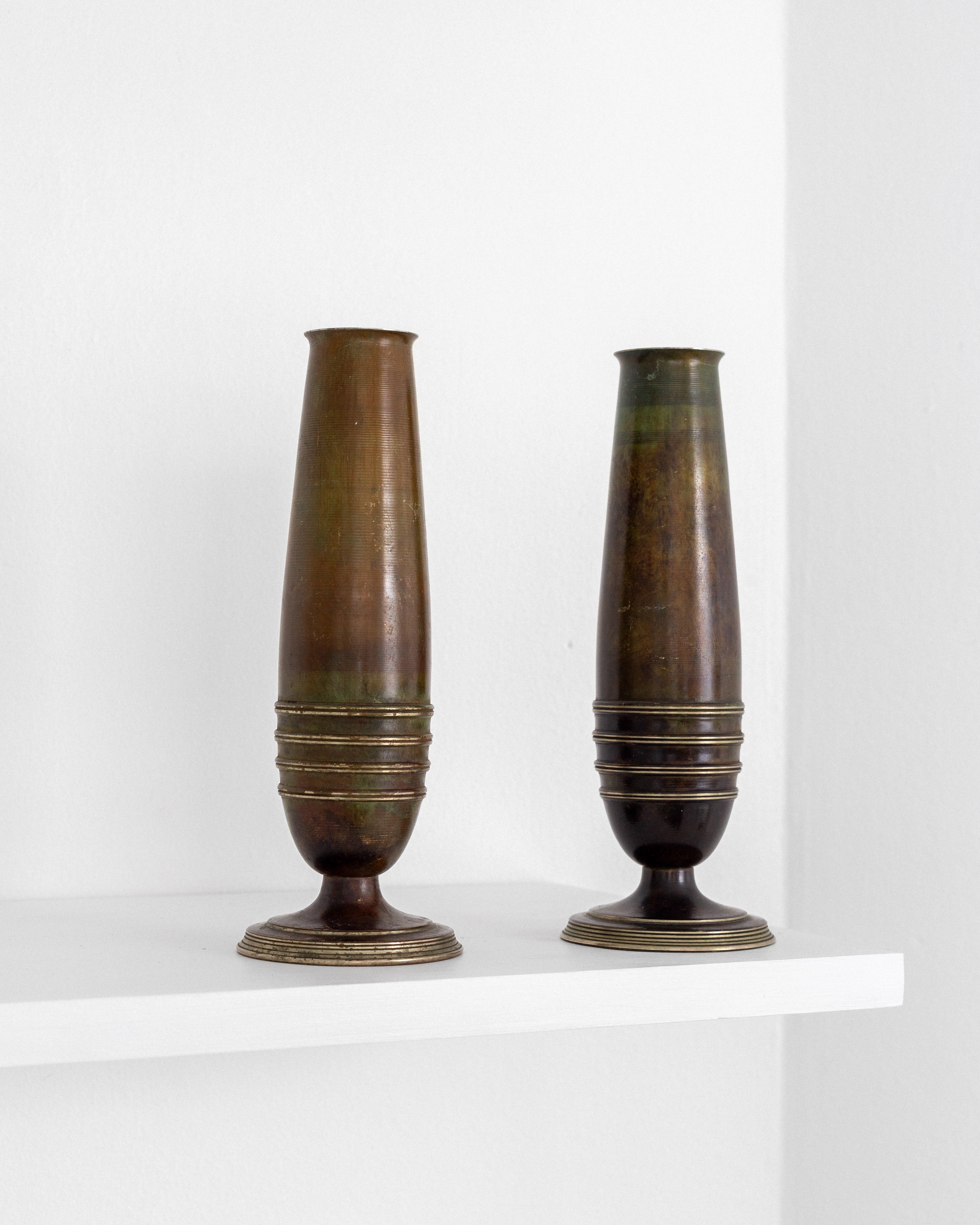 Pair of Modernist Brass and Bronze Vases — displayed on white shelf against wall