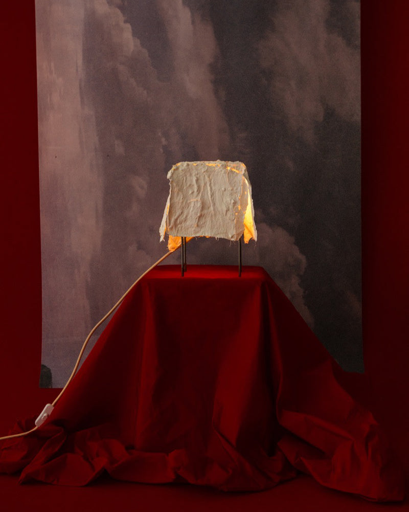 Contemporary table lamp with draped parchment shade on red fabric