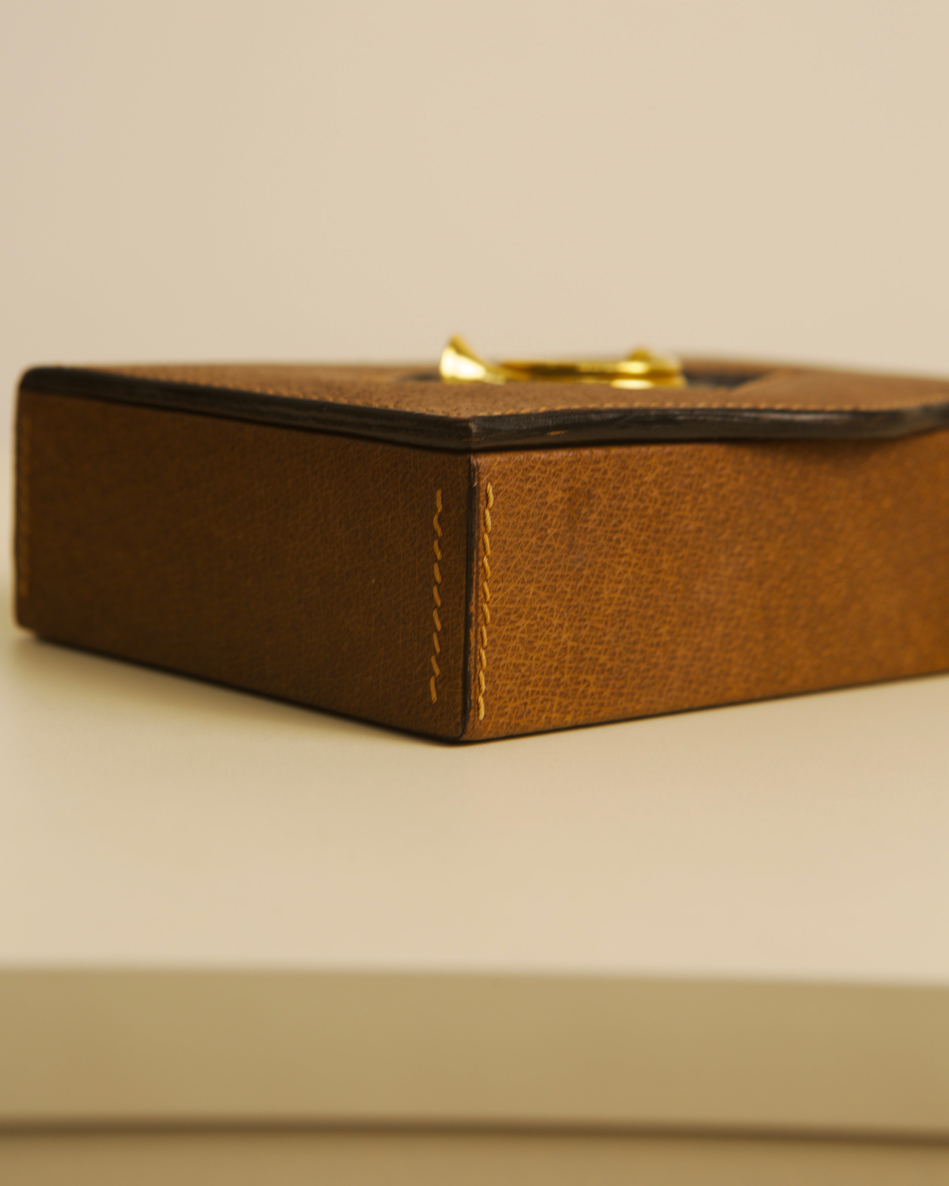 Brown leather Gucci box detail showing corner stitching and brass clasp