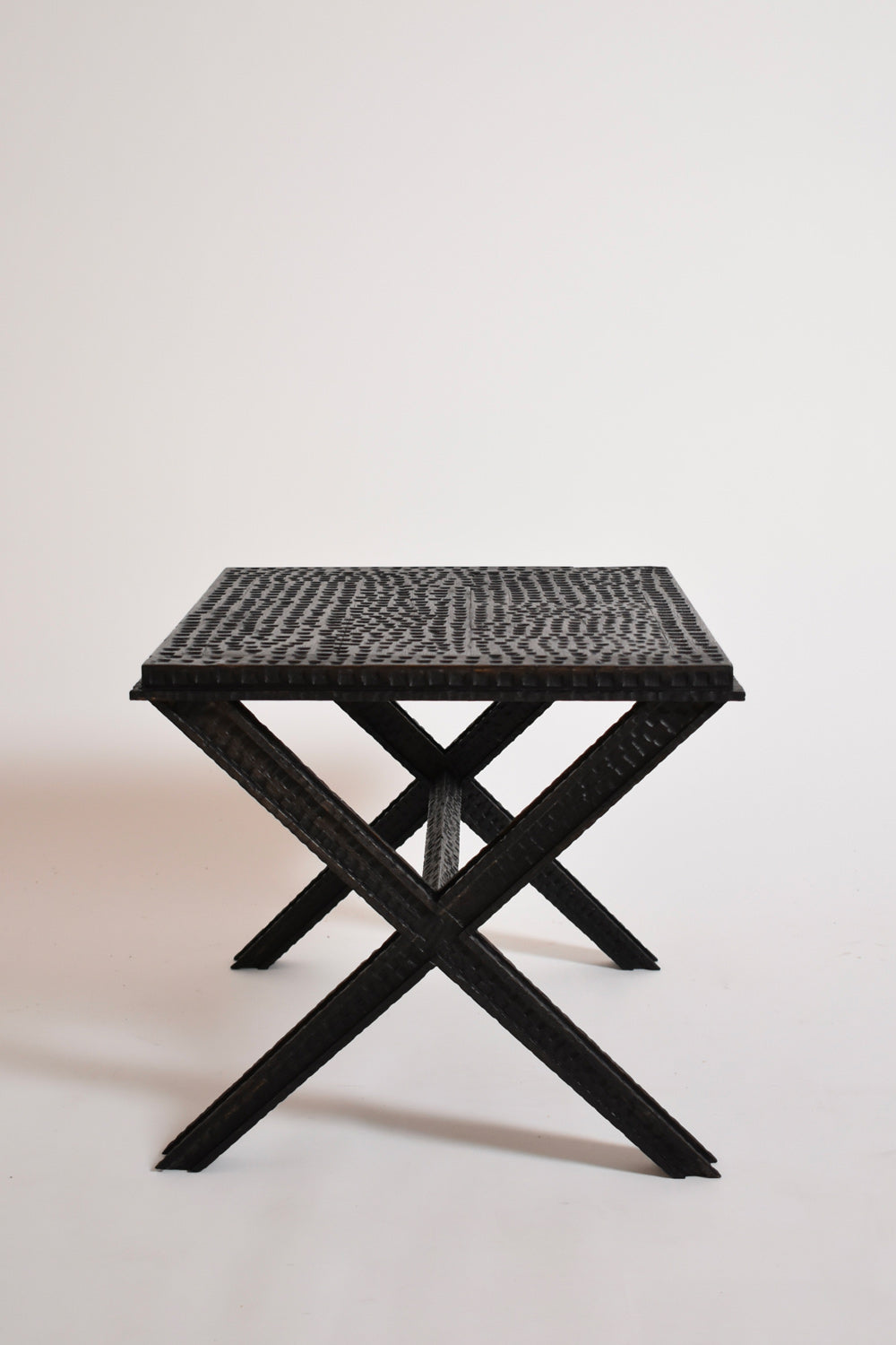 Brutalist Gouged Wood Coffee Table — angled view of textured black wood surface