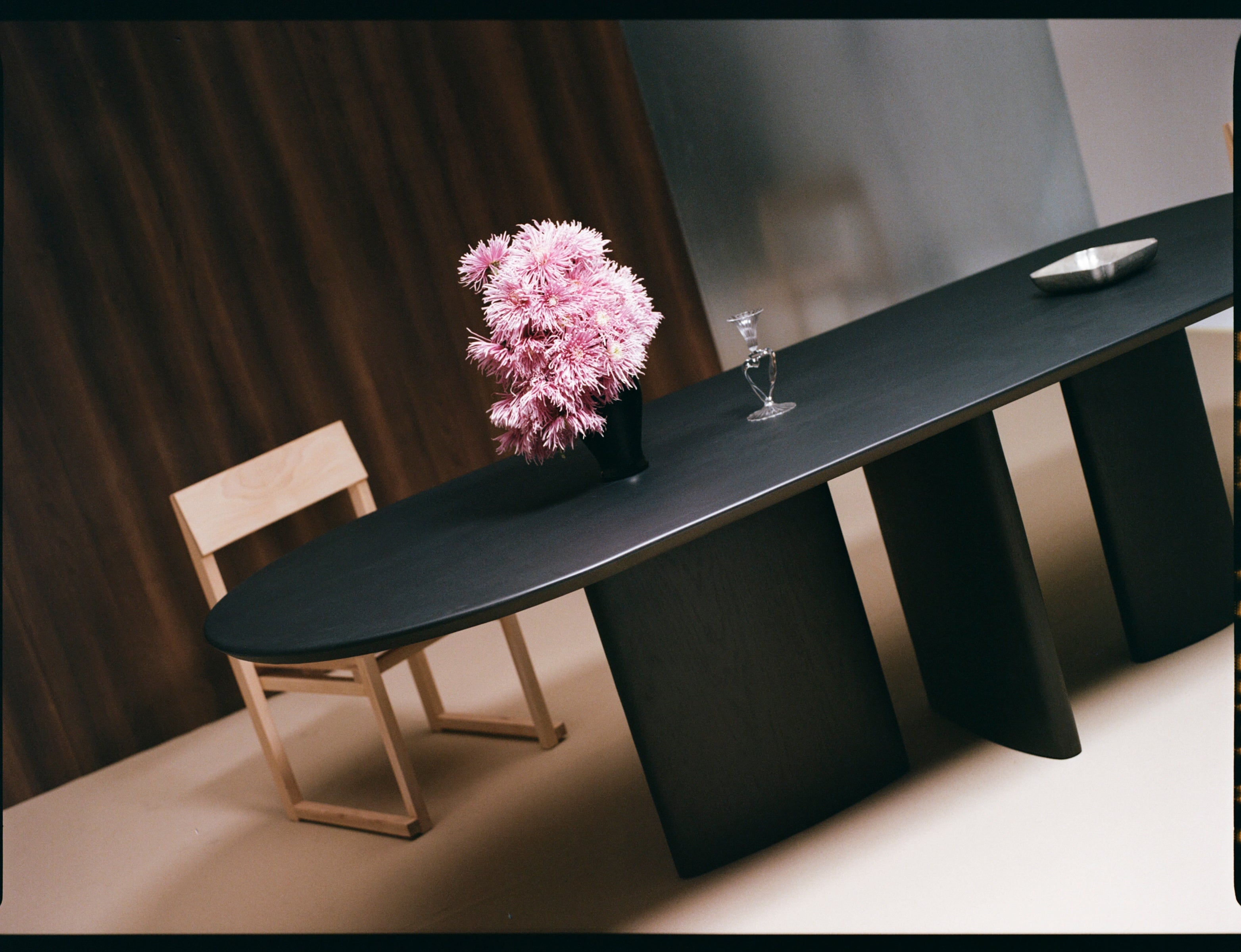 Valerie Dining Table — angled view with black surface and floral centerpiece