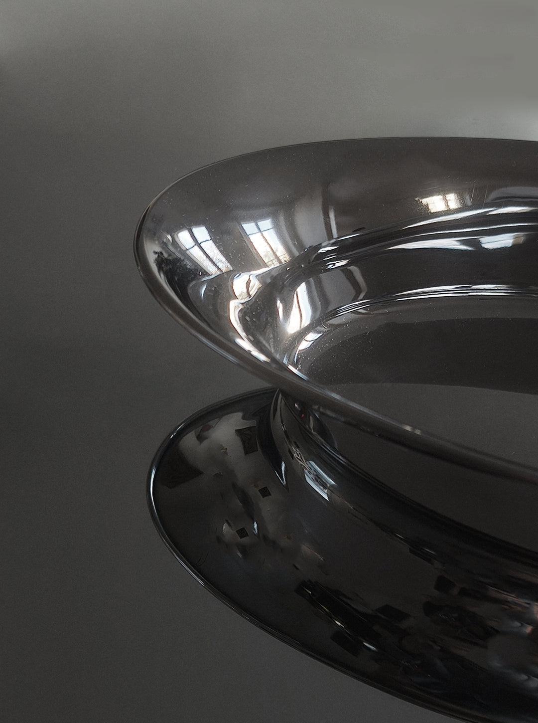 Oval Steel Dish — side angle showing reflective surface on dark backdrop