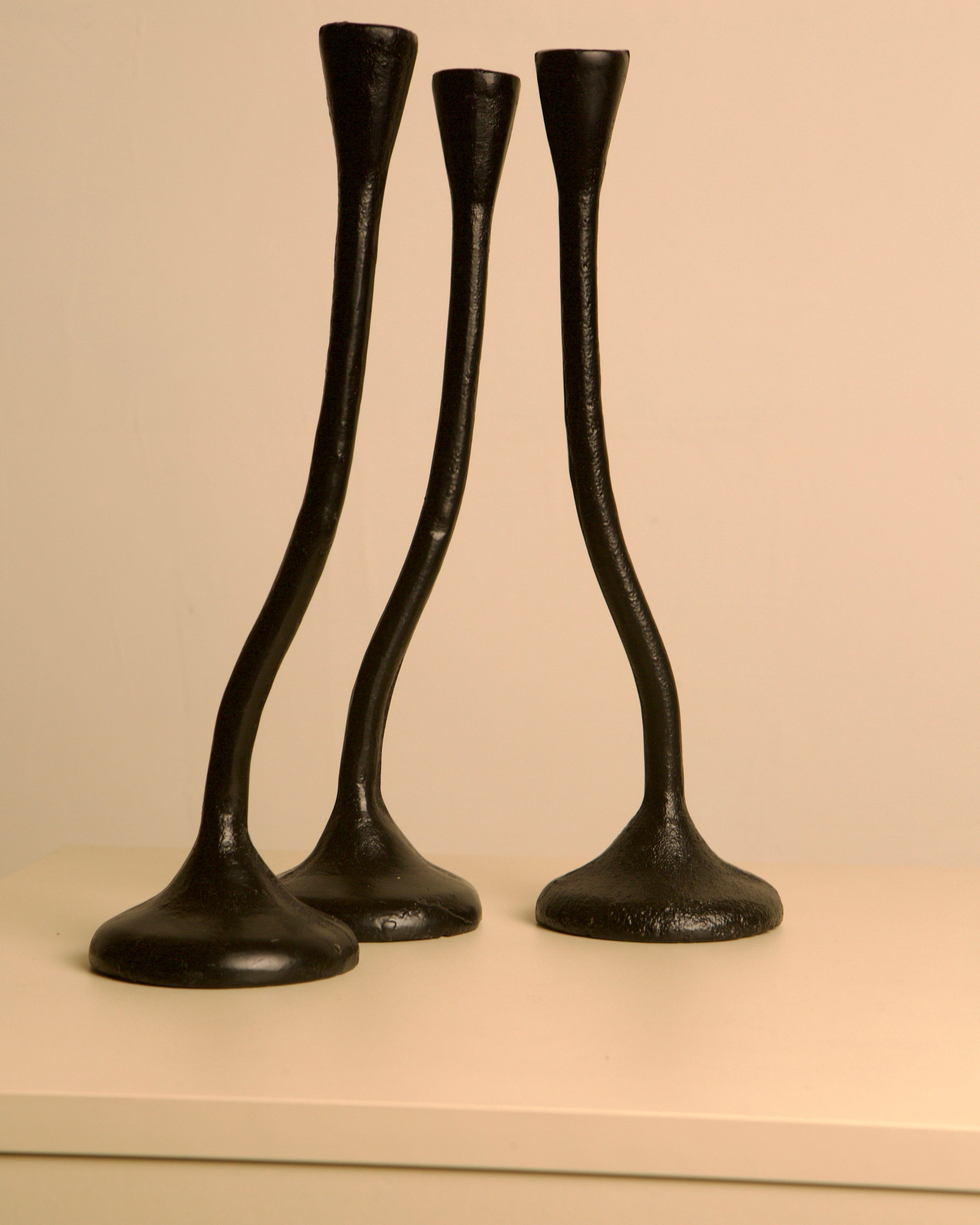 Set of 3 "Twisted" Candleholders in Black Cast Aluminum, 80s — angled view on light-colored surface