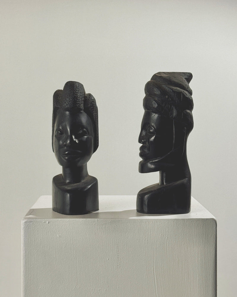 Pair of carved ebony African busts on white pedestal display