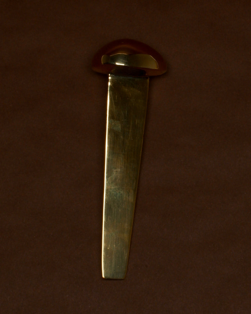 MOMI Bookmark No. 1 — close-up of brass bookmark on brown background