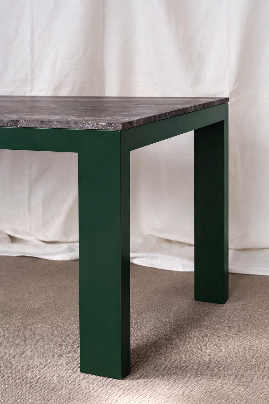 Firme Dining Table — close-up of green metal legs and textured top