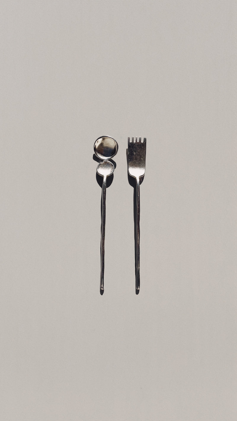 Modern silver tea spoon and fork cutlery set on beige background
