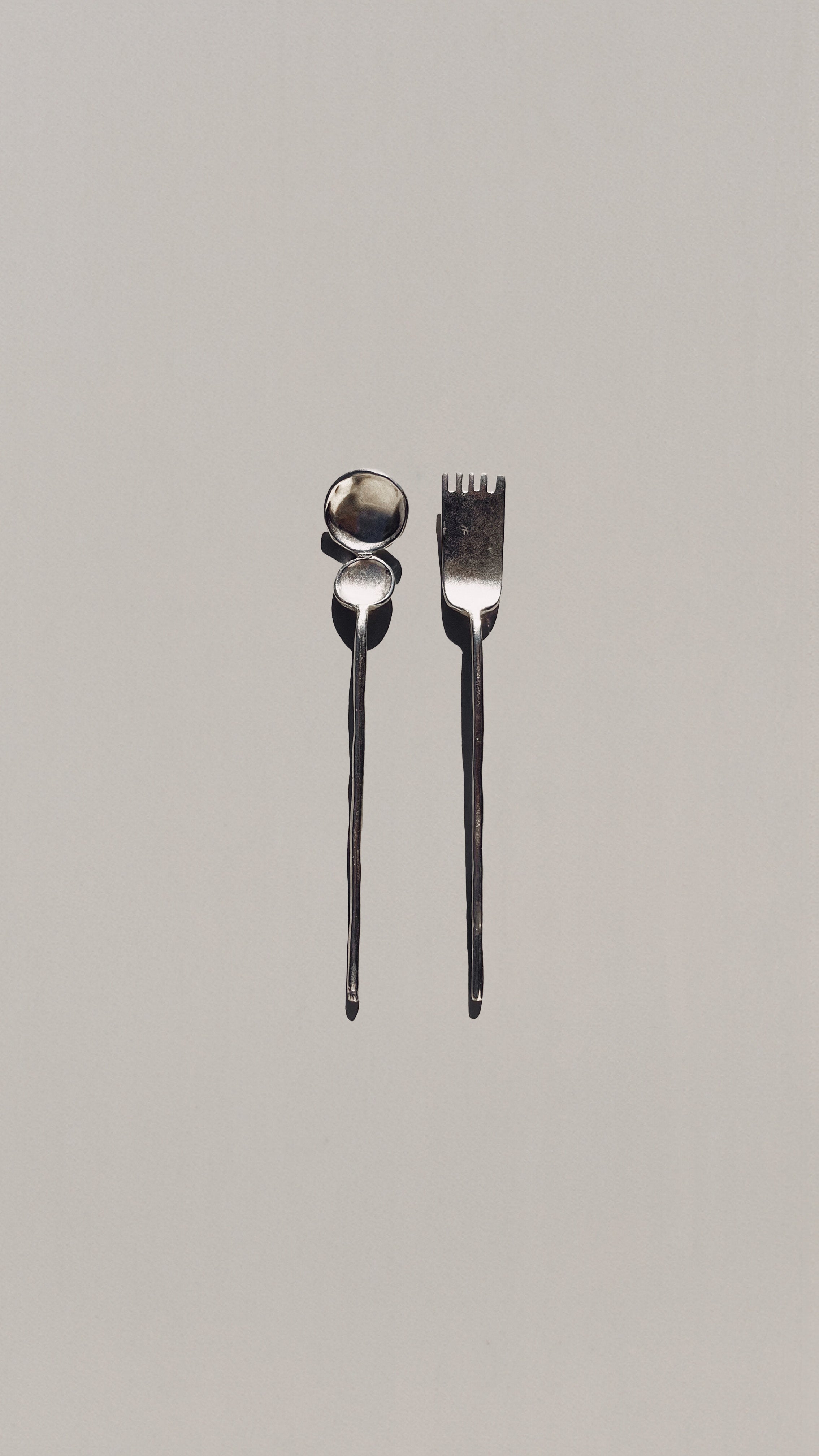 Modern silver tea spoon and fork cutlery set on beige background