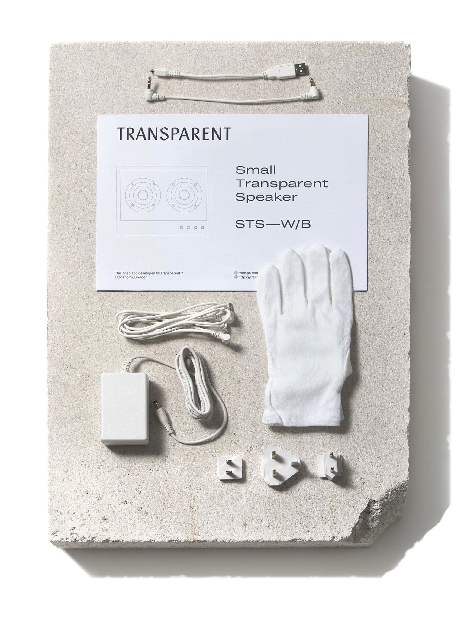 Small Transparent Speaker White - Bluetooth — back view with accessories on concrete surface