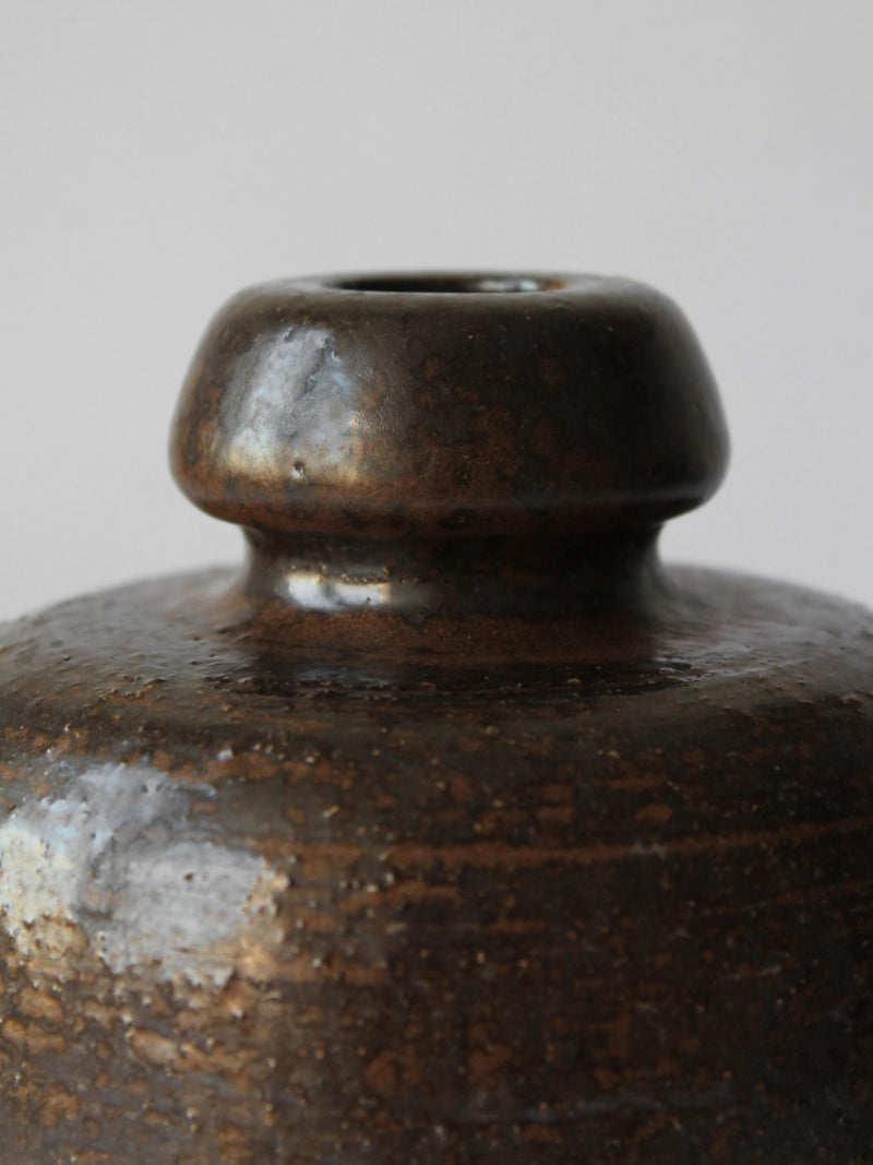 Close-up detail of ceramic vase neck and glazed brown finish