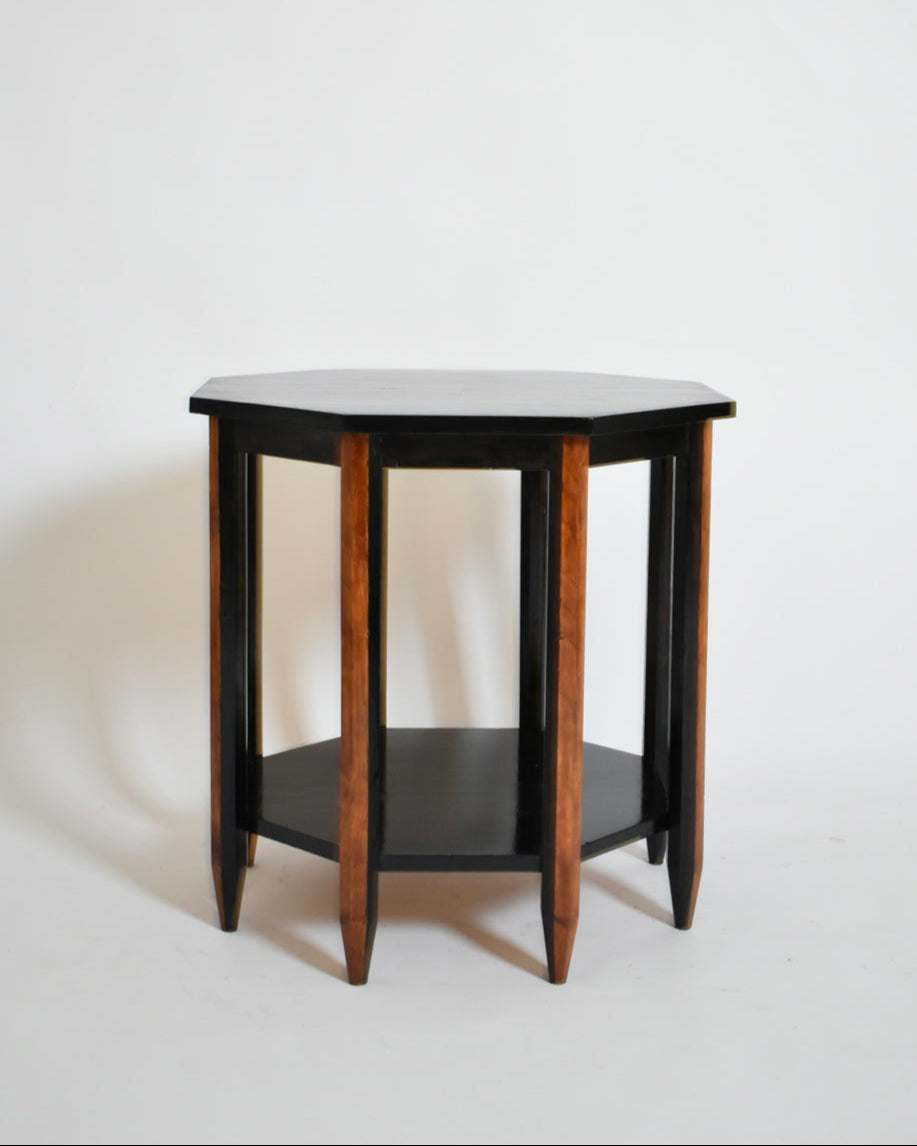 The Octogonal Modernist Side Table, 1920s by Barracuda Interiors features a wooden octagonal top, tapered legs, lower shelf, and warm brown and black finishes. Set against a plain white background.