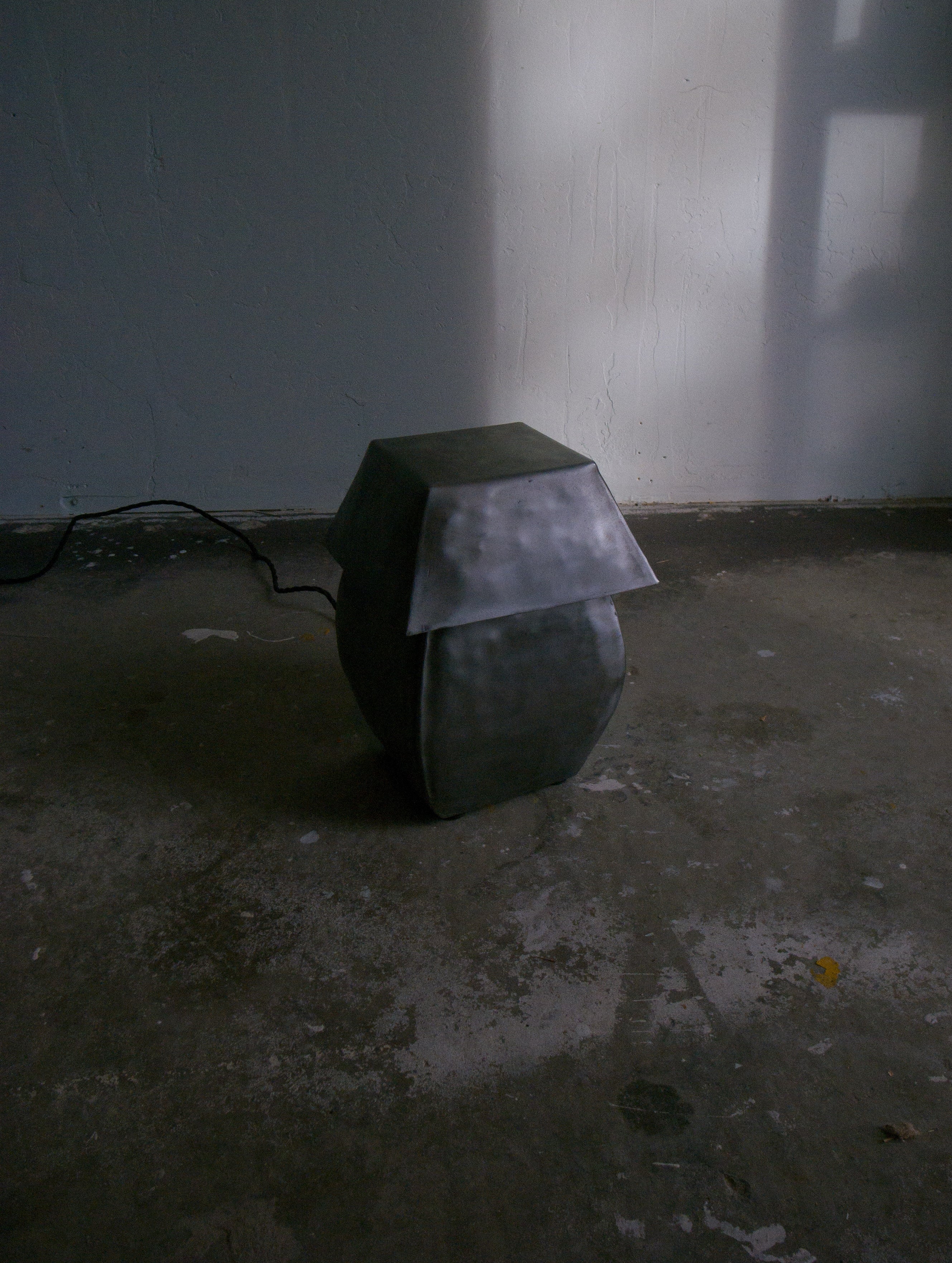 Hammered steel table lamp with angular shade in moody interior