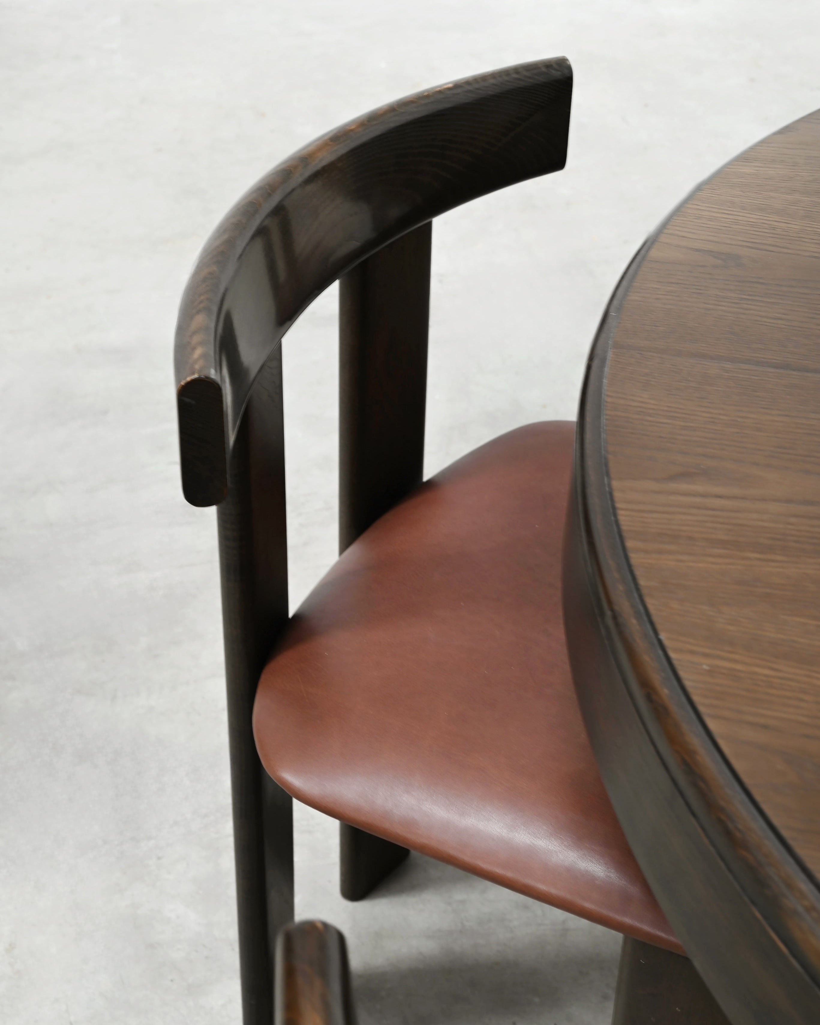 Close-up detail of curved walnut backrest and cognac leather seat