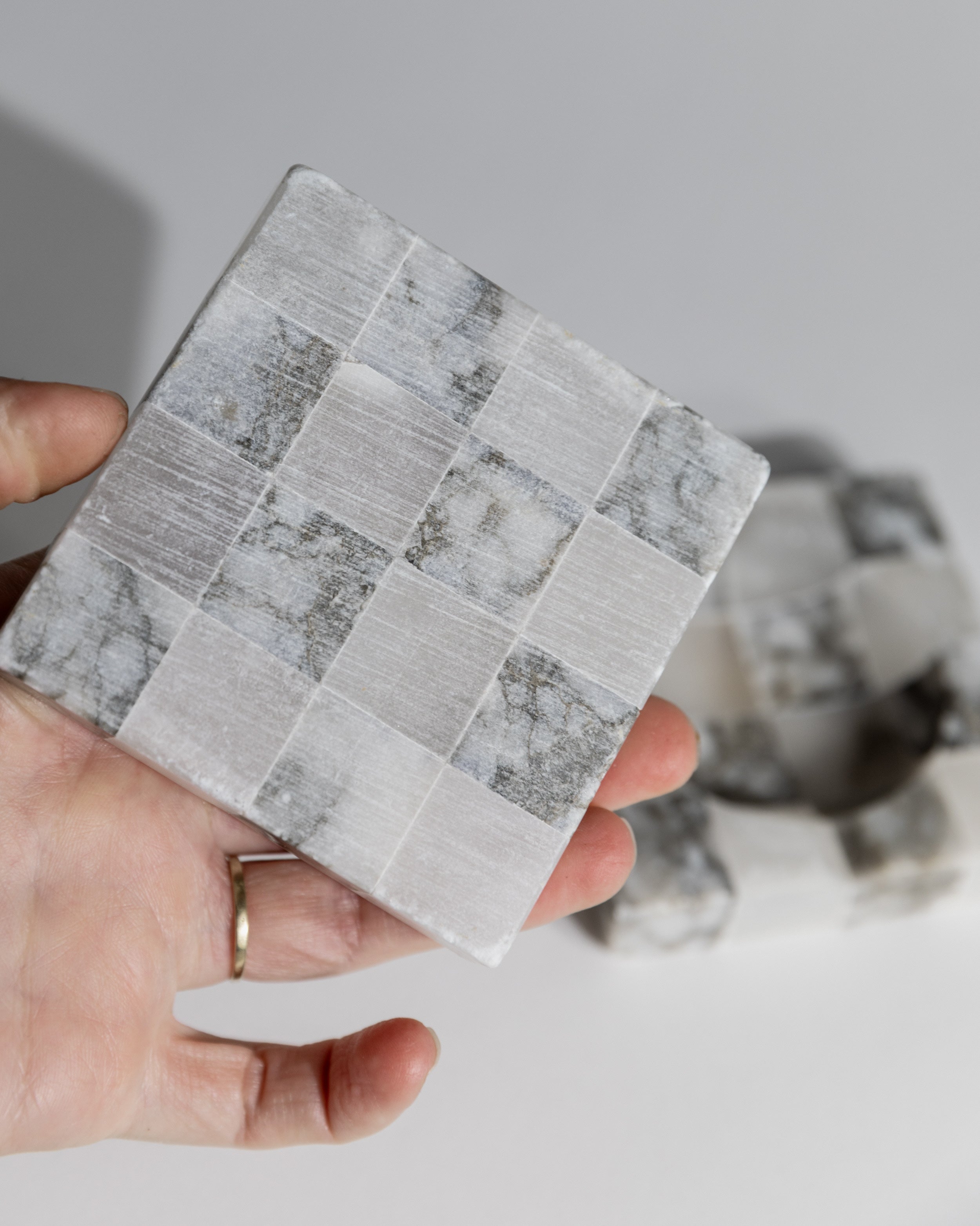 Hand-held marble mosaic tile sample showing gray and white pattern